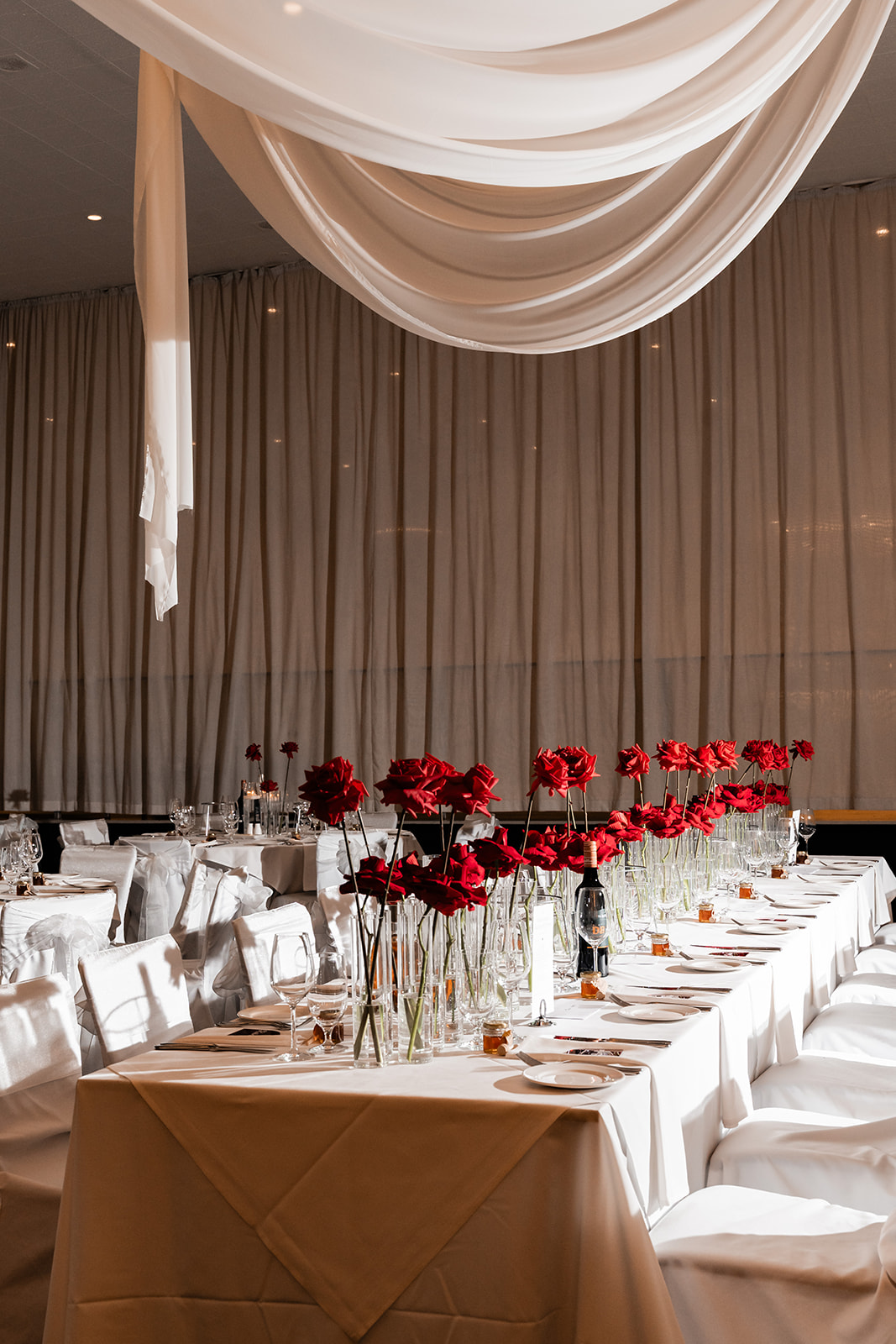 Long reception table styled in bloom with crimson roses and candles