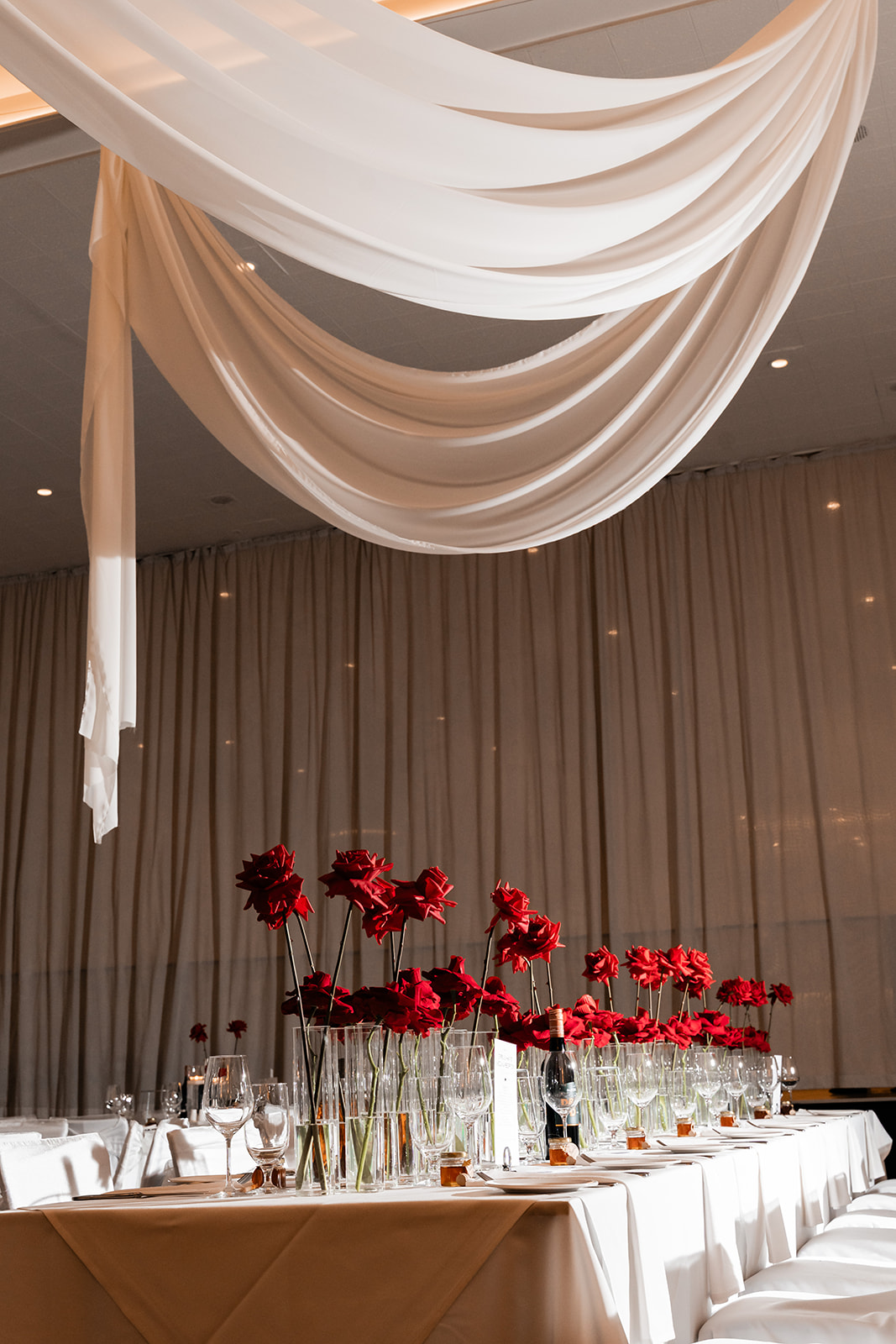 Ivory draped wedding ceremony backdrop with red floral installation