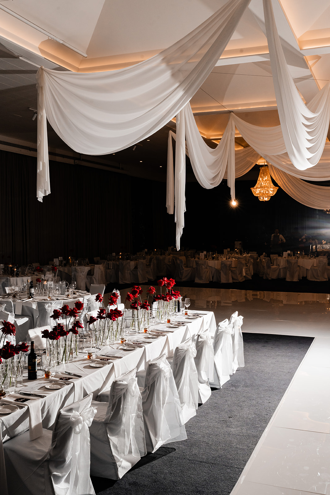 Red-toned wedding reception room with layered florals and candlelight